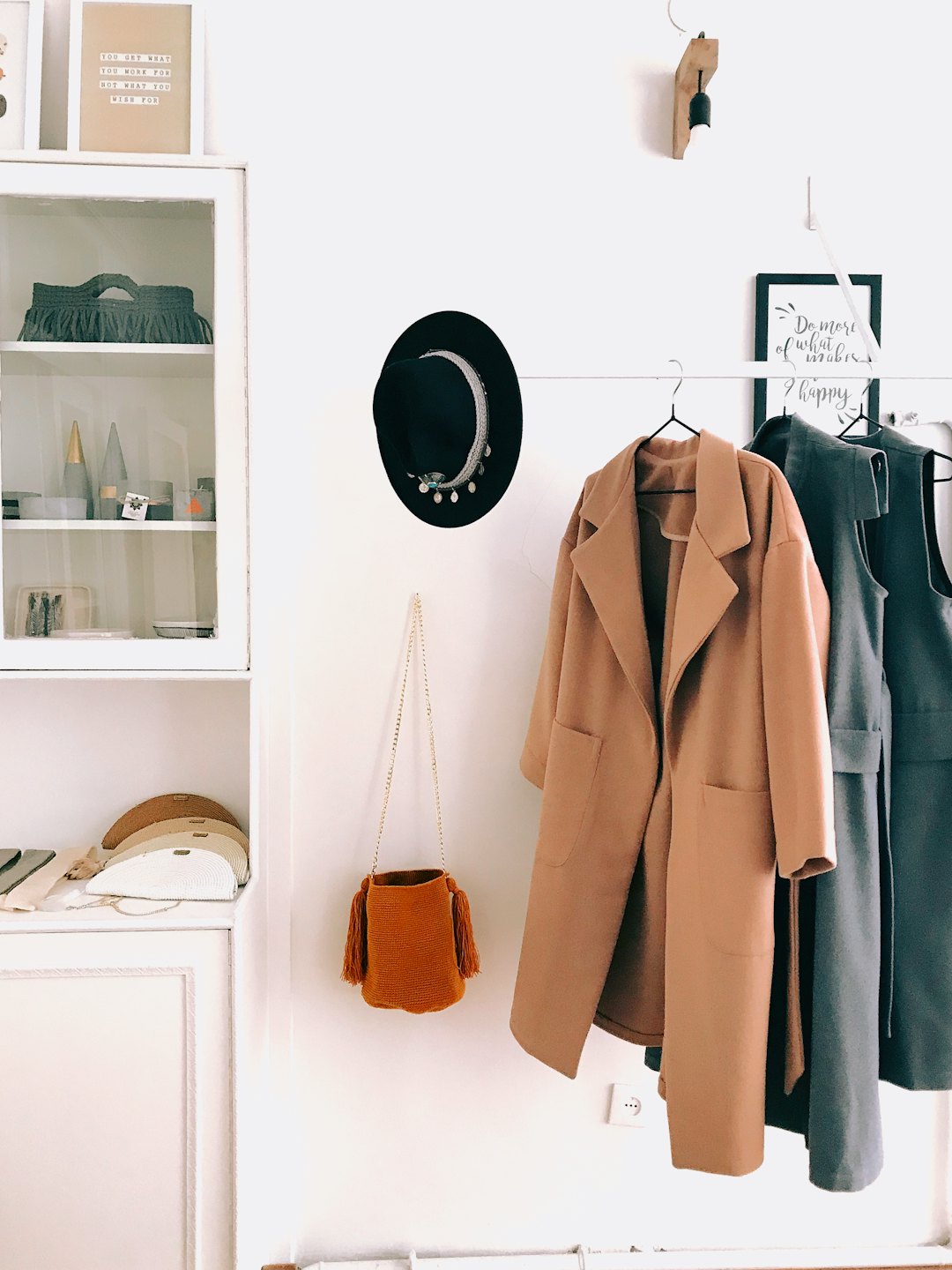 Stylish camel coat and grey dress on a rack with accessories.